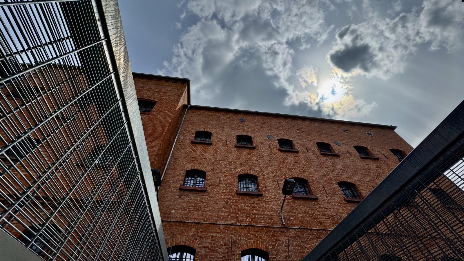 Blick vom Hof durch Metallgitter zum Backsteingebäude und Himmel über der ehemaligen Stasi-Untersuchungshaftanstalt Andreasstraße in Erfurt